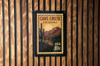 A framed poster of a cactus and mountains, with the text "CAVE CREEK ARIZONA" and "USA 10c" printed on it, is displayed on a wooden wall.