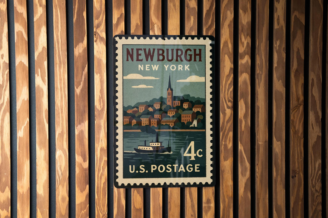 A vintage postage stamp from New York featuring a boat on a river, mounted on a wooden wall.
