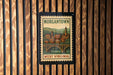 A vintage-style postage stamp depicting the town of Morgantown, West Virginia, with a bridge and buildings in the background.