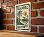 A vintage postage stamp from Tamarac, Florida, featuring a palm tree and sunset landscape.