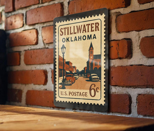 A vintage-style postage stamp from Stillwater, Oklahoma, featuring a street scene and a church, mounted on a brick wall.