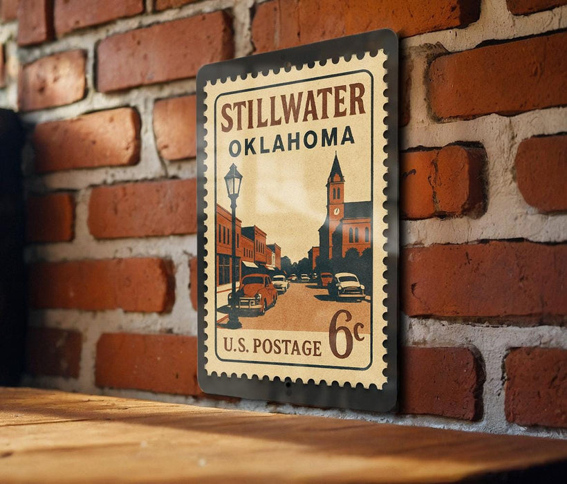 A vintage-style postage stamp from Stillwater, Oklahoma, featuring a street scene and a church, mounted on a brick wall.