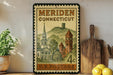 A vintage postage stamp from Meriden, Connecticut, featuring a church and a clock tower, displayed on a shelf with kitchen utensils and a potted plant.