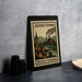A framed illustration of a town in Pennsylvania, featuring a church, steam-powered factory, and a bridge, is displayed on a table.