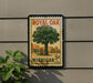A vintage-style postage stamp featuring a tree and a store, mounted on a wall.