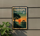 a vintage-style sign for Fairhope, Alabama, with a sunset scene and a pier in the background.