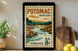 A vintage-style postage stamp from the United States, featuring a scenic landscape of Potomac, Maryland, with a river flowing through the rocky terrain.