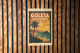 A vintage-style postage stamp from California, featuring a palm tree and a beach scene, is displayed on a wooden wall.