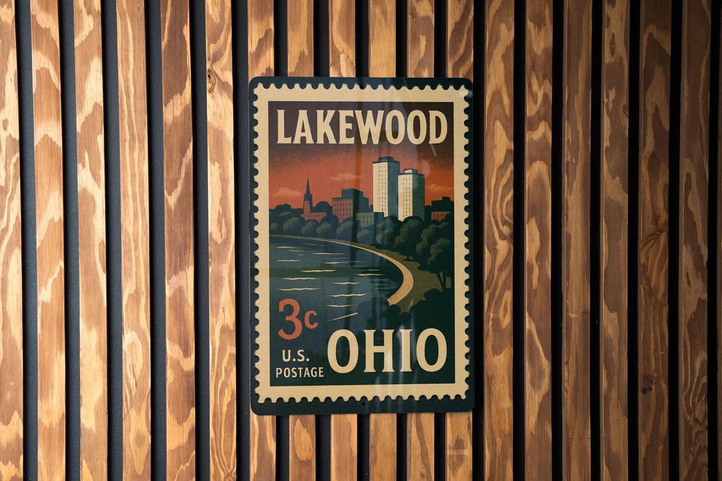 A vintage-style postage stamp from the United States, featuring a cityscape and a river, is displayed on a wooden wall.