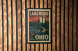 A vintage-style postage stamp from the United States, featuring a cityscape and a river, is displayed on a wooden wall.