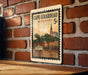 A vintage-style postage stamp depicting a boat on a river, with a brick wall and a church in the background, hanging on a brick wall.