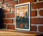 A vintage-style postage stamp from the United States, featuring the city of Cincinnati, Ohio, with a bridge and skyline in the background.