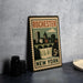 A vintage-style metal sign with the text "Rochester New York" and a cityscape illustration, placed on a gray countertop next to some black camera lenses.