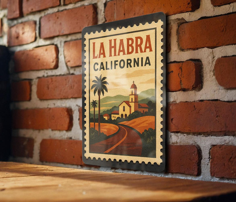 A vintage-style metal sign with the text "LA HABRA CALIFORNIA" displayed on a brick wall.