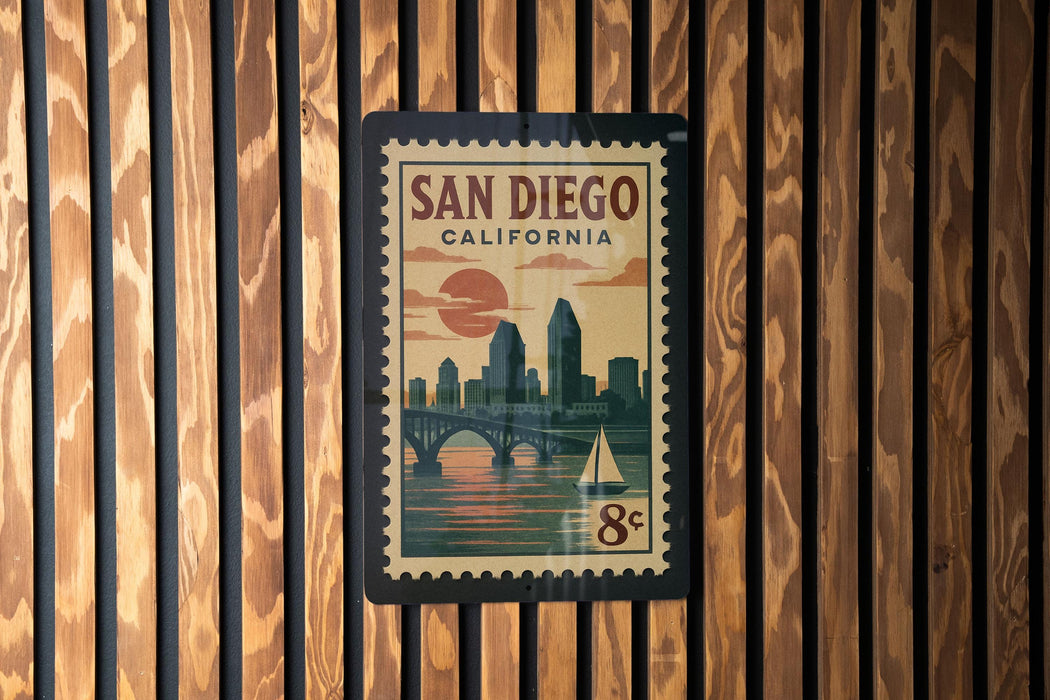 A vintage-style postage stamp from San Diego, California, featuring a cityscape and a sailboat, mounted on a wooden wall.