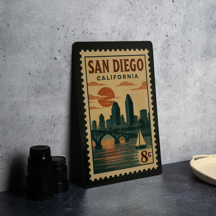 A framed poster of San Diego, California, featuring a cityscape and a sailboat, is displayed on a table.