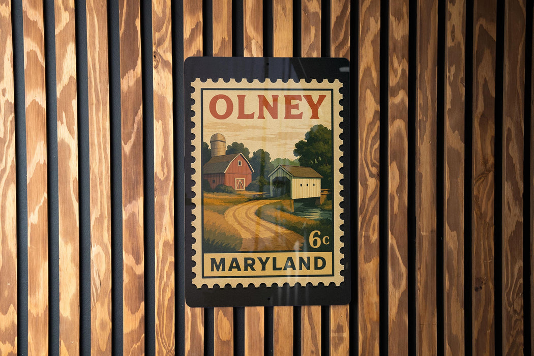 A vintage-style postage stamp from Maryland, featuring a rural landscape with a barn and a road, is displayed on a wooden wall.