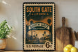 A vintage-style postage stamp from South Gate, California, featuring a street scene and palm trees, is displayed on a shelf next to a wooden cutting board and some lemons.