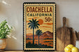 A vintage-style poster of Coachella, California, featuring palm trees and mountains, is displayed on a wall next to a wooden cutting board and a potted plant.