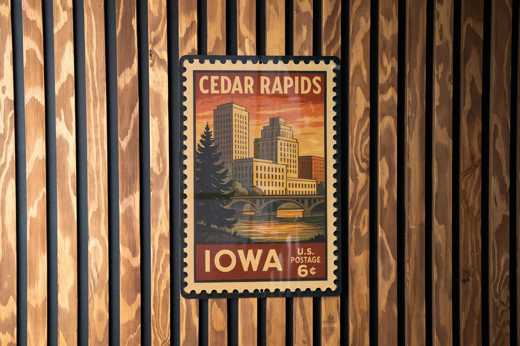 A vintage-style postage stamp from Cedar Rapids, Iowa, featuring a cityscape and a bridge, mounted on a wooden wall.