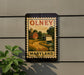 A vintage-style metal sign with a farm scene and barn, mounted on a wall.