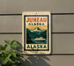 A sign for Juneau, Alaska, featuring a mountain landscape with a ferry boat in the background.