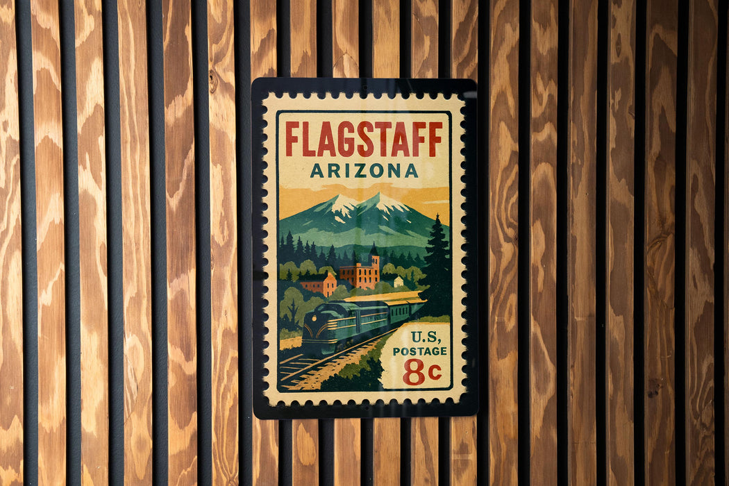 A vintage-style postage stamp from Flagstaff, Arizona, featuring a train and mountains in the background.
