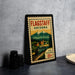A vintage-style postage stamp from Flagstaff, Arizona, featuring a train and mountains, placed on a countertop next to some camera equipment.