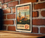 A vintage postage stamp from Hattiesburg, Mississippi, featuring a water tower and other buildings, mounted on a brick wall.