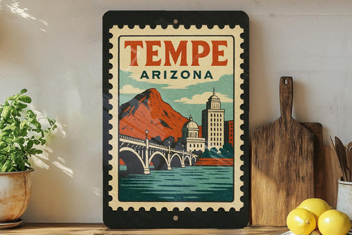 A framed poster of Tempe, Arizona, featuring a bridge and mountains, is displayed on a shelf next to a wooden cutting board and some lemons.