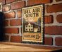 A metal sign with the text "BEL AIR SOUTH" and "MARYLAND 15¢" is displayed on a brick wall.