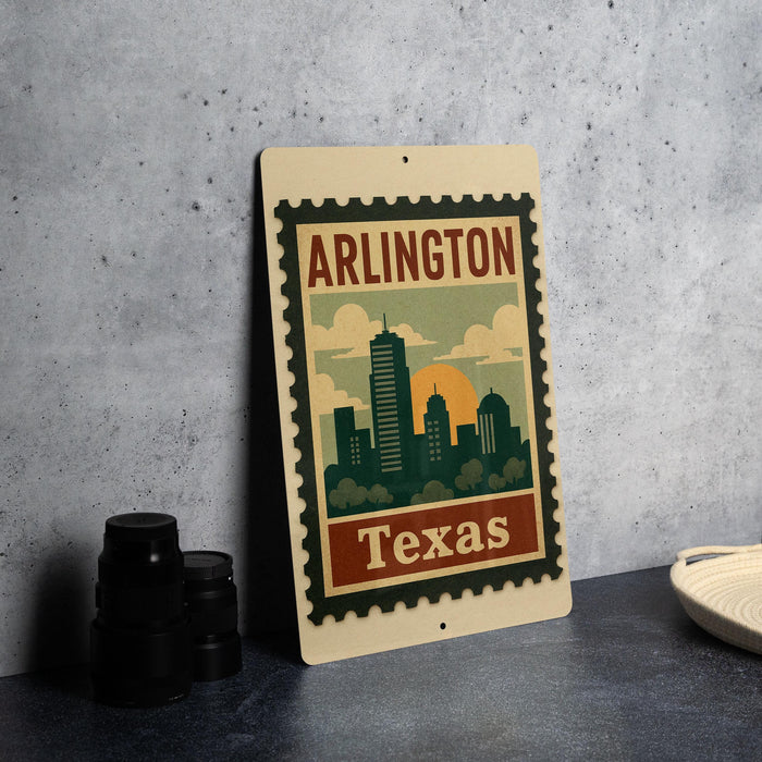 A vintage-style metal sign with the text "ARLINGTON TEXAS" and an illustration of a city skyline, placed on a gray countertop next to some black camera lenses.