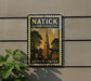 A vintage-style postage stamp from Massachusetts, featuring a church steeple and a town scene, is displayed on a wall.