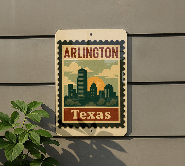A vintage-style sign with the text "ARLINGTON TEXAS" and a graphic of a city skyline, mounted on a gray wall next to a plant.