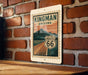 A metal sign with a vintage-style illustration of Route 66 in Arizona, mounted on a brick wall.