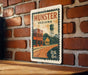 A vintage-style postage stamp from Munster, Indiana, featuring a brick wall and a water tower, mounted on a wooden surface.