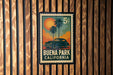 A vintage postage stamp from Buena Park, California, featuring a classic car and palm trees against a sunset background.
