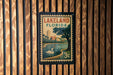 A vintage-style postage stamp from Lakeland, Florida, featuring a serene lake, palm trees, and a swan, is displayed on a wooden wall.