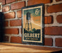 A vintage postage stamp featuring a water tower in Gilbert, Arizona, with the text "6c" and "GILBERT ARIZONA" printed on it.