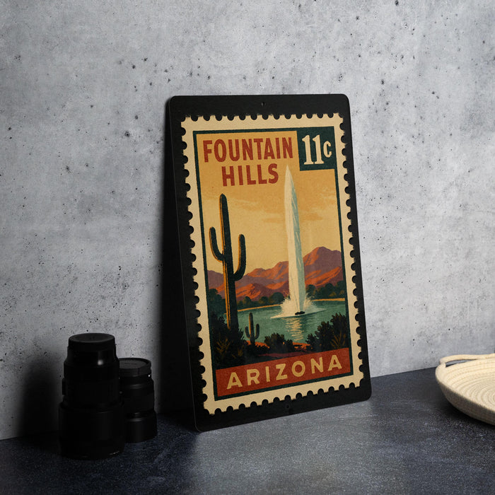 A framed vintage postage stamp depicting the Fountain Hills in Arizona, with a desert landscape and a tall fountain in the background.