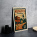 a vintage-style metal sign with a colorful illustration of a town scene, including a water tower, buildings, and a road.