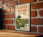 A vintage-style metal sign with a floral design and text, mounted on a brick wall.