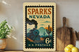 A vintage-style postage stamp from Sparks, Nevada, featuring a train and desert landscape, is displayed on a shelf next to a wooden cutting board and some lemons.