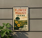A vintage-style metal sign with a floral design and text, mounted on a wall next to a plant.