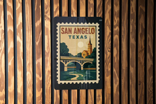 A vintage-style postage stamp from San Angelo, Texas, featuring a bridge and trees, is displayed on a wooden wall.