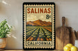 A framed vintage postage stamp depicting a farm scene in California, with mountains in the background and a field of crops in the foreground.