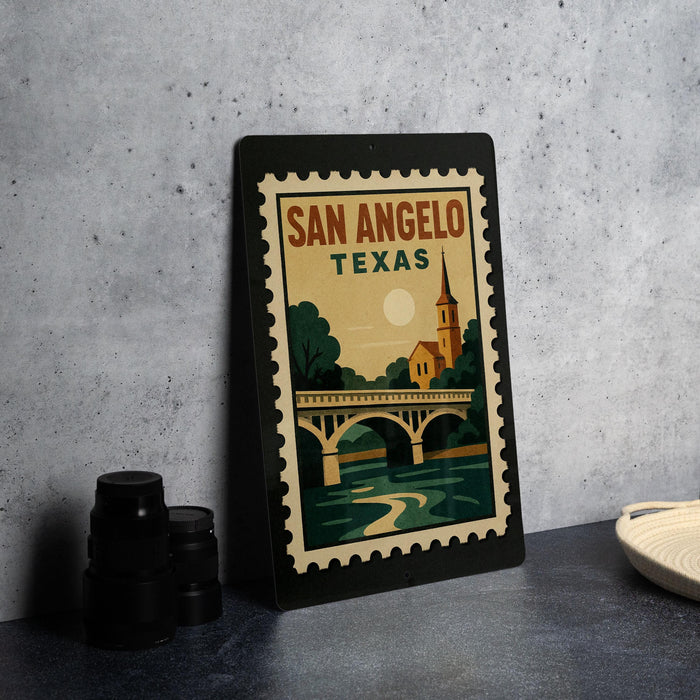 A framed poster of San Angelo, Texas, featuring a bridge and a church, is displayed on a table.