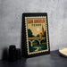 A framed poster of San Angelo, Texas, featuring a bridge and a church, is displayed on a table.