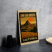 A framed vintage-style poster of San Luis Obispo, California, featuring a mountain landscape with a sunset.