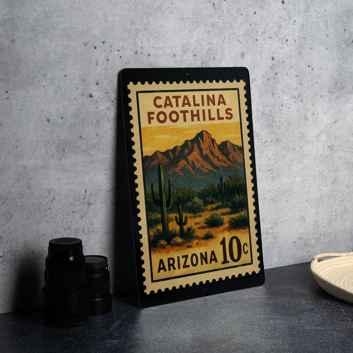 A metal sign with a desert landscape and mountains, featuring the text "Catalina Foothills Arizona 10¢" on it.